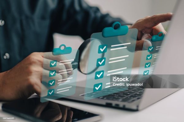 Businessman use magnifying glass with a checklist on clipboard paper. Successfully complete business assignments.